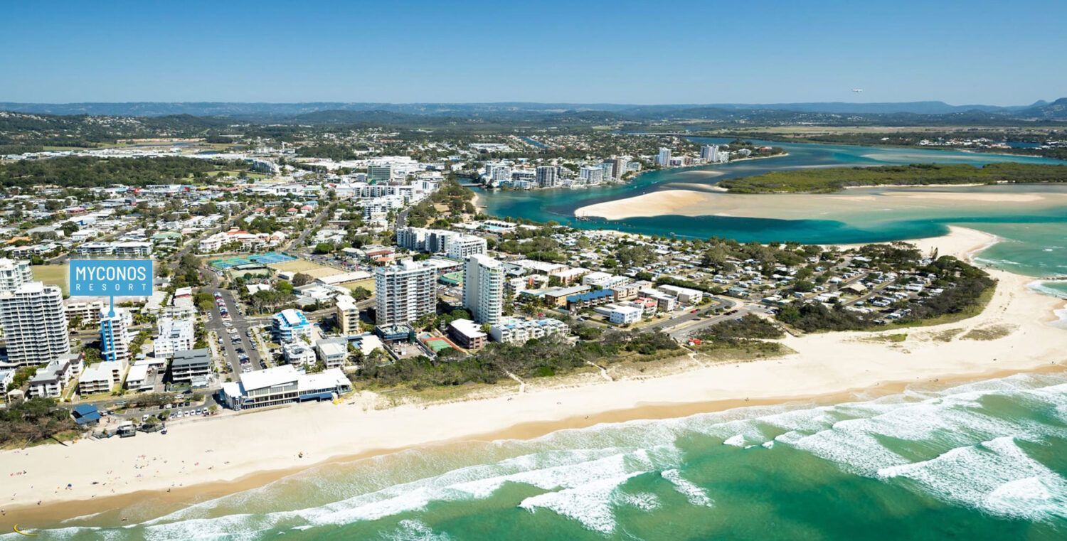 Coastal town aerial view with beach, buildings, and blue water.