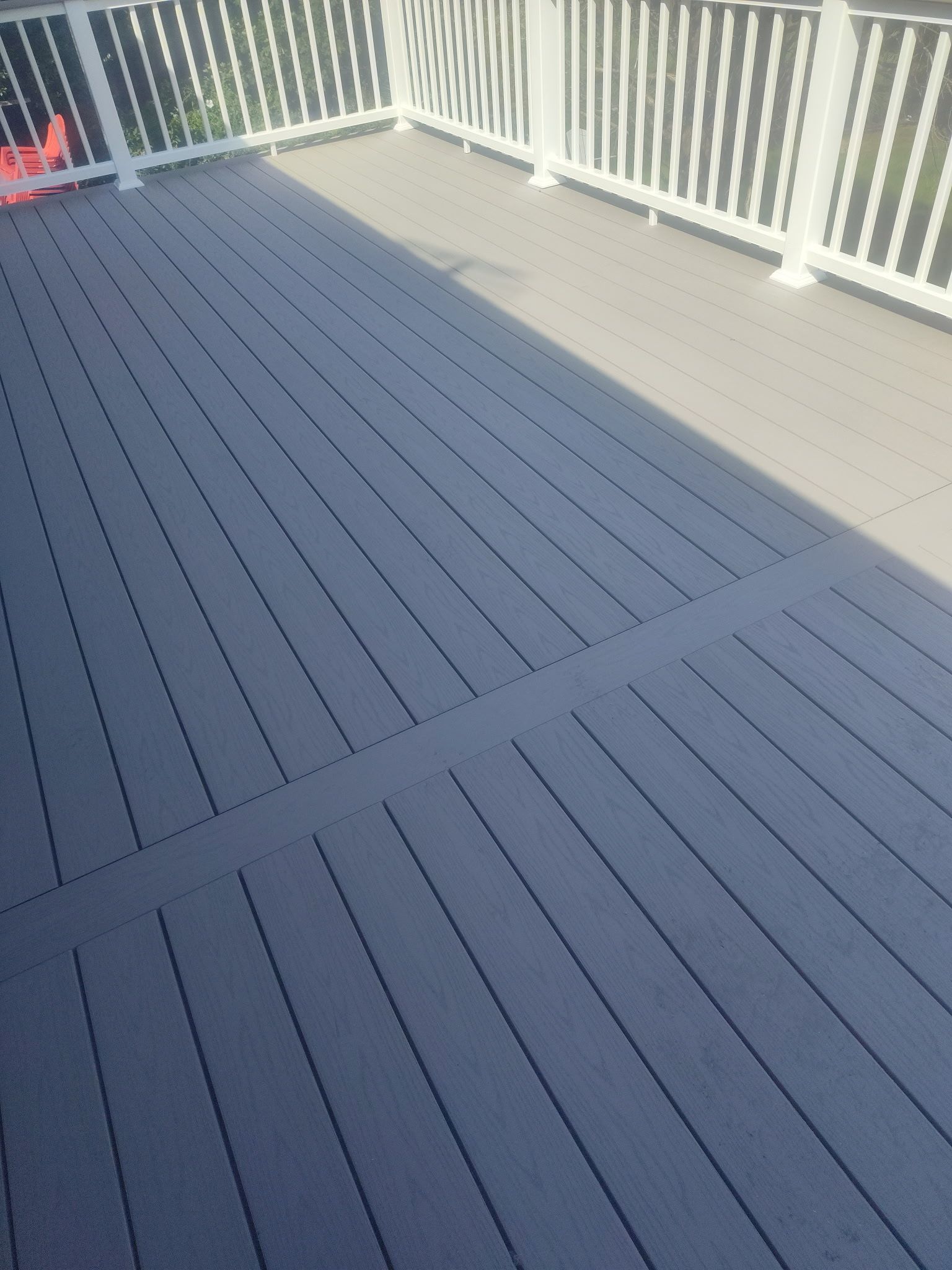 Blue composite deck with white railings and a gray walkway in bright daylight