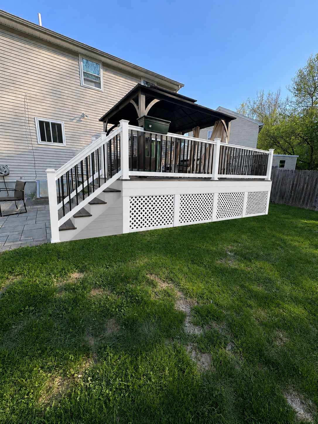 White wooden porch ramp with railings and a covered patio beside a stone house on a grassy lawn.