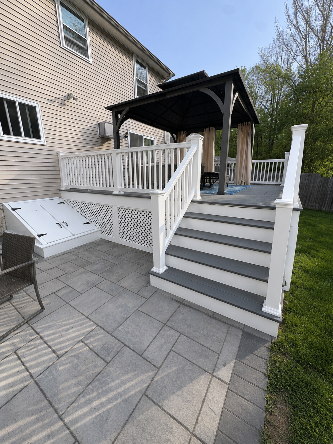 White-railed steps and ramp leading to a covered porch beside a brick house.