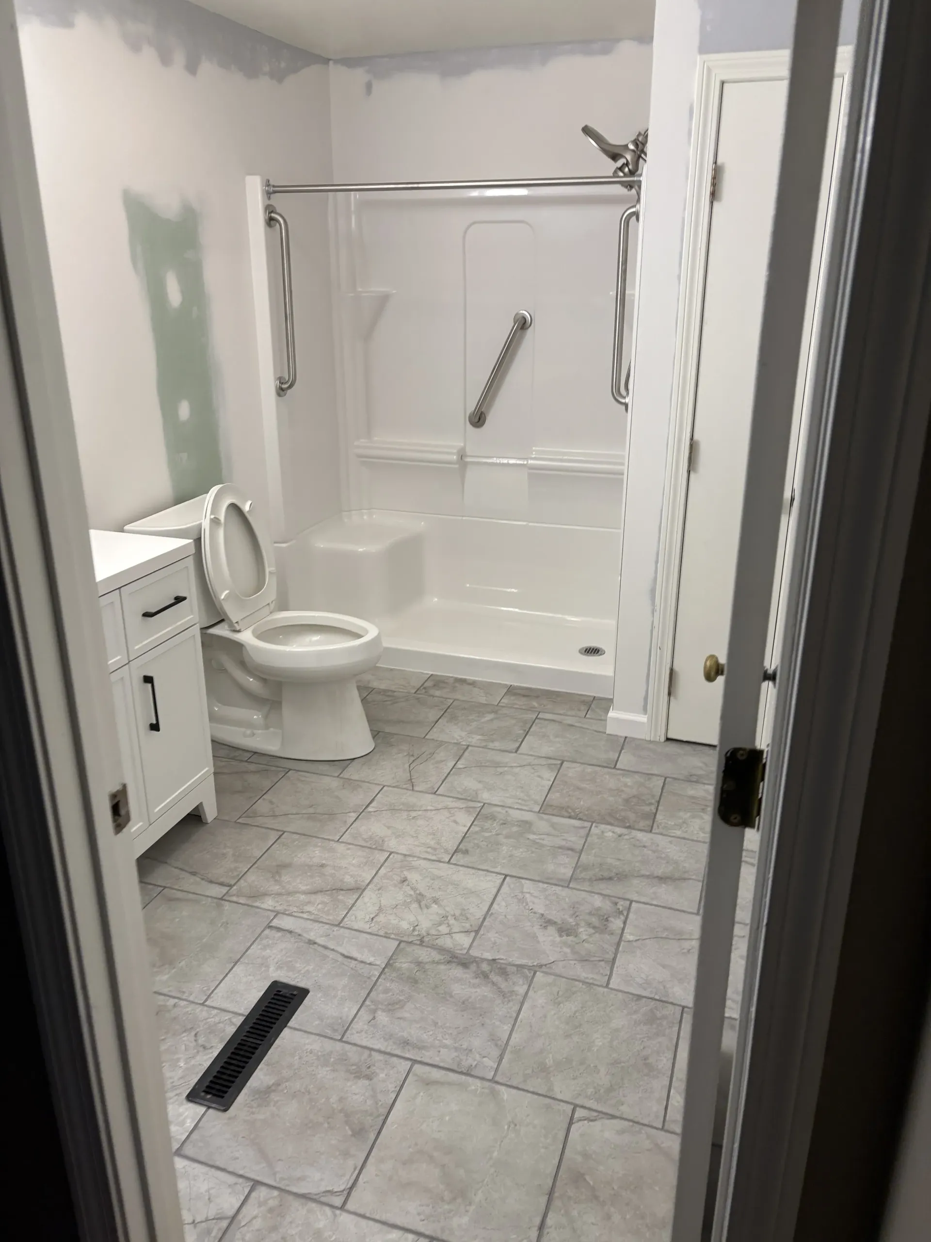 Small unfinished bathroom with toilet, sink, tiled floor, and walk-in shower.