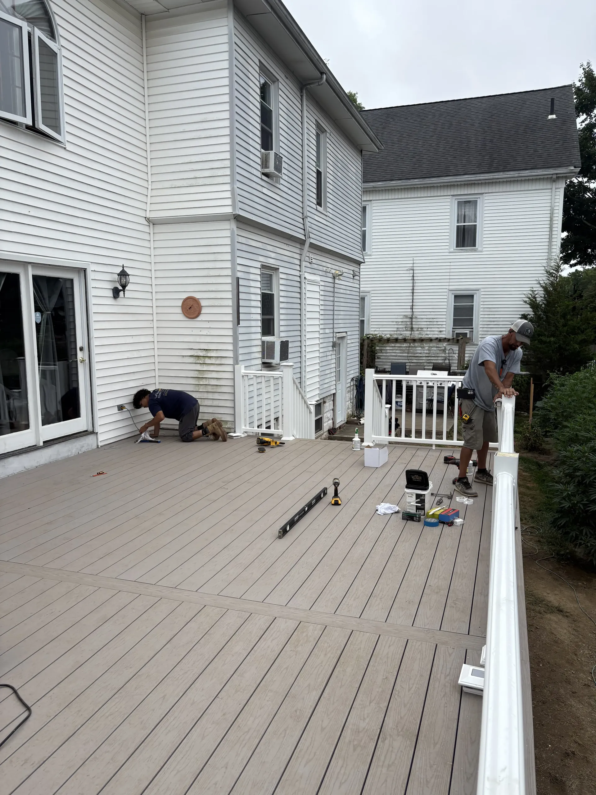 White house deck under construction with tools scattered and two workers near the wall