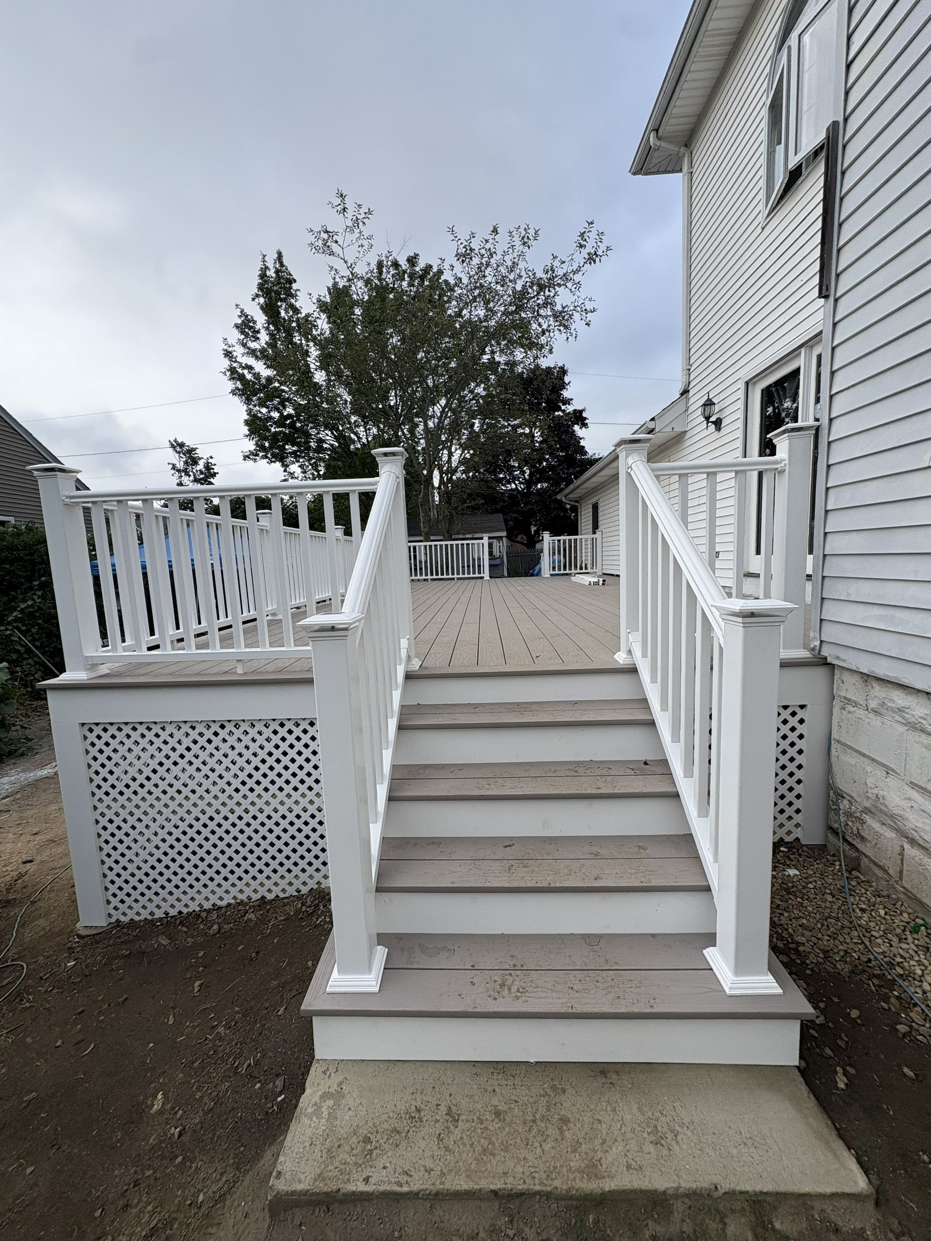 White wooden front steps with railings leading up to a gray house porch.
