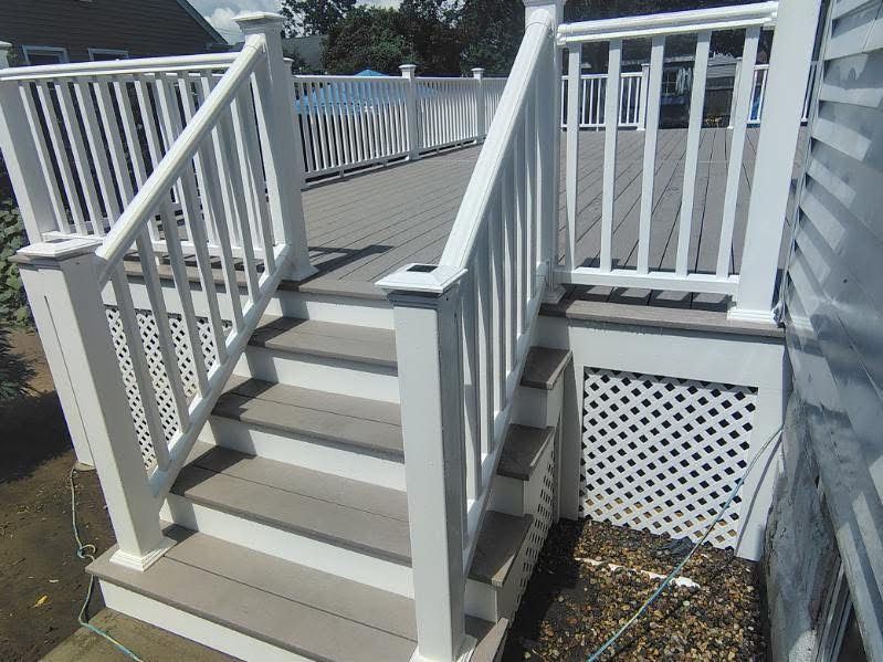 White exterior wooden stairs with railings leading to a porch beside a house