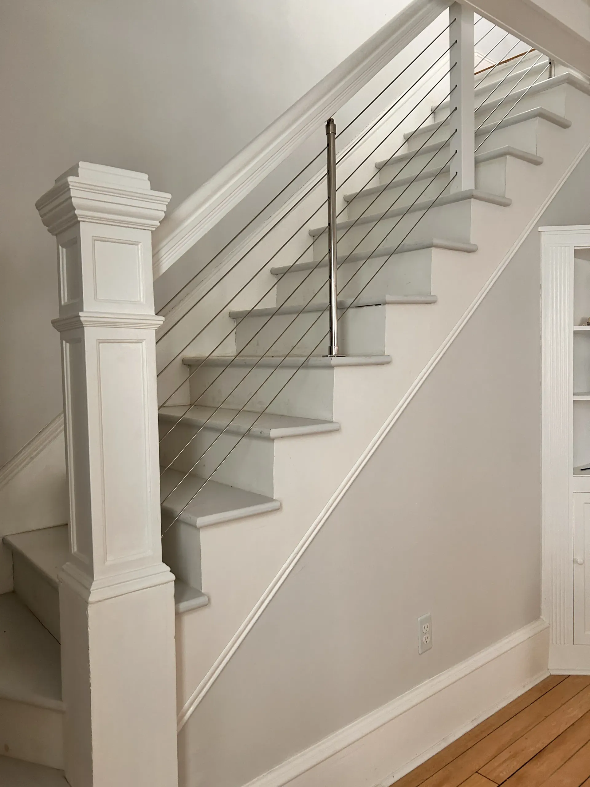 White staircase with carpeted steps and banister in a beige interior hallway