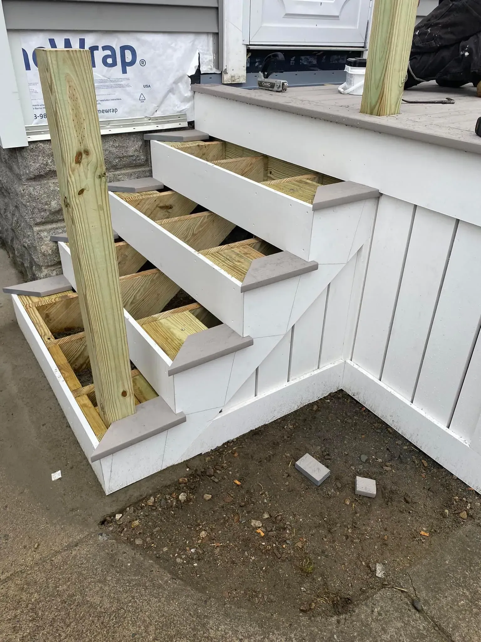 Open staircase with white trim and unfinished treads beside a house porch.