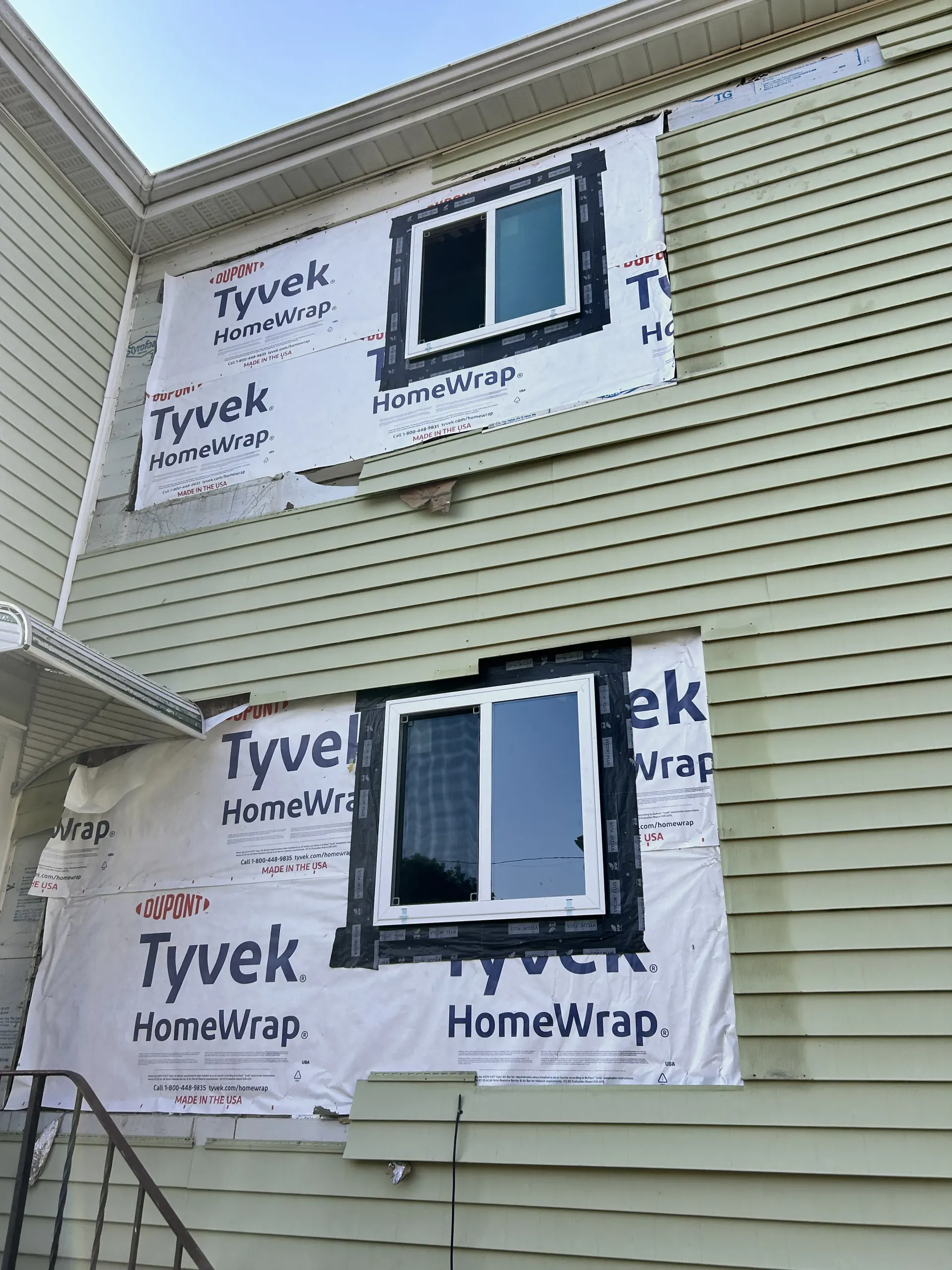 House exterior with new Tyvek house wrap and two windows during siding repair