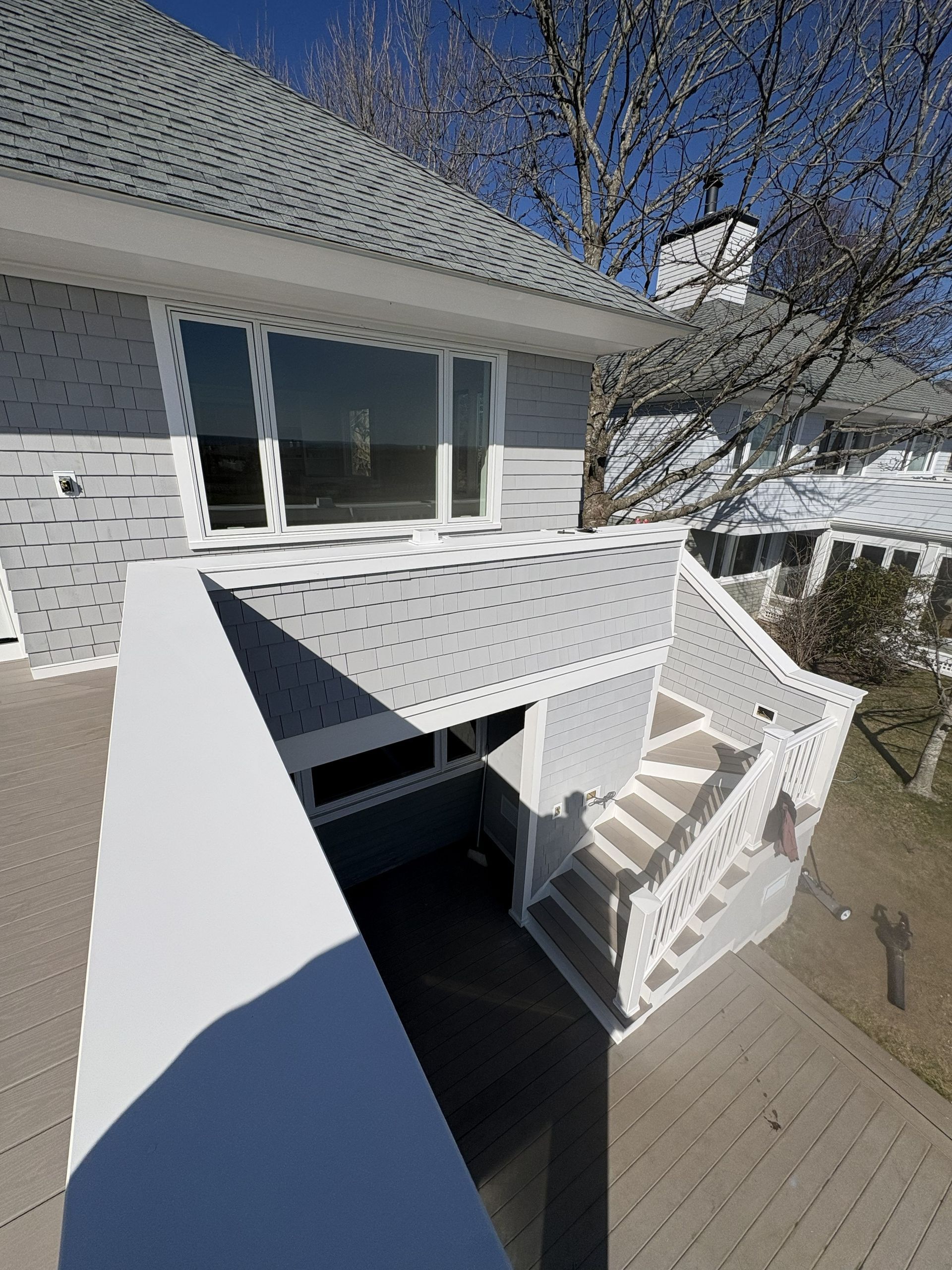 Brick house entrance with white stairs leading down to a dark basement door under a small porch.