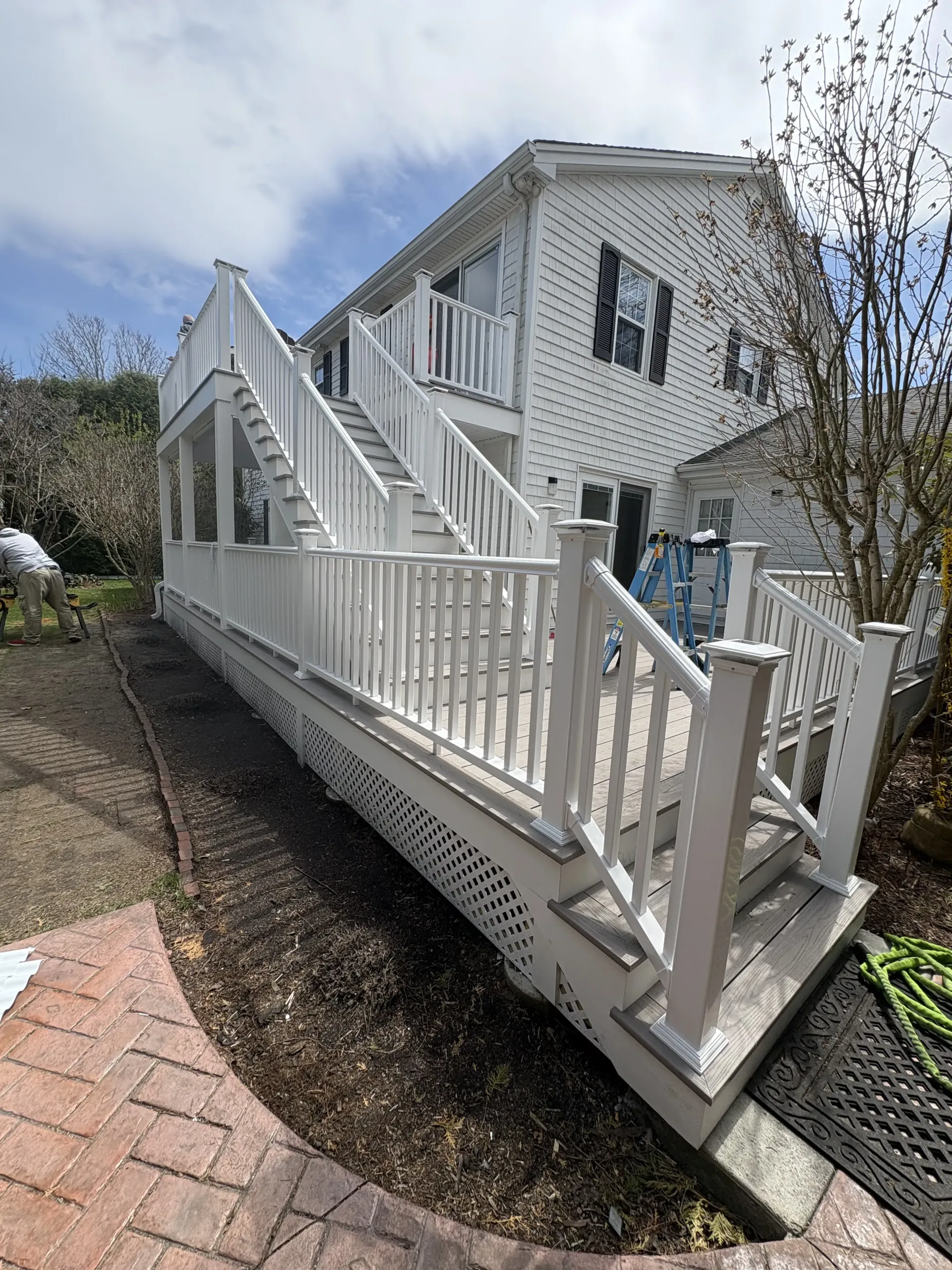 White house with a wheelchair-accessible ramp and railings beside a brick walkway under a cloudy sky