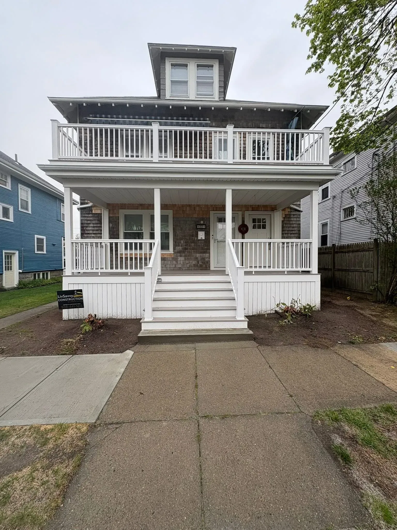 White two-story house with front porch, stairs, and central walkway on a cloudy day