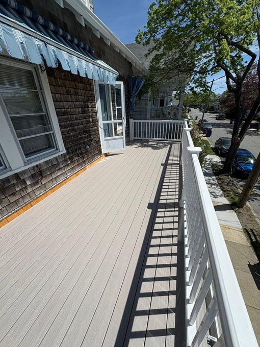 Sunny porch with white railing, blue awning, and a view of a tree-lined street.