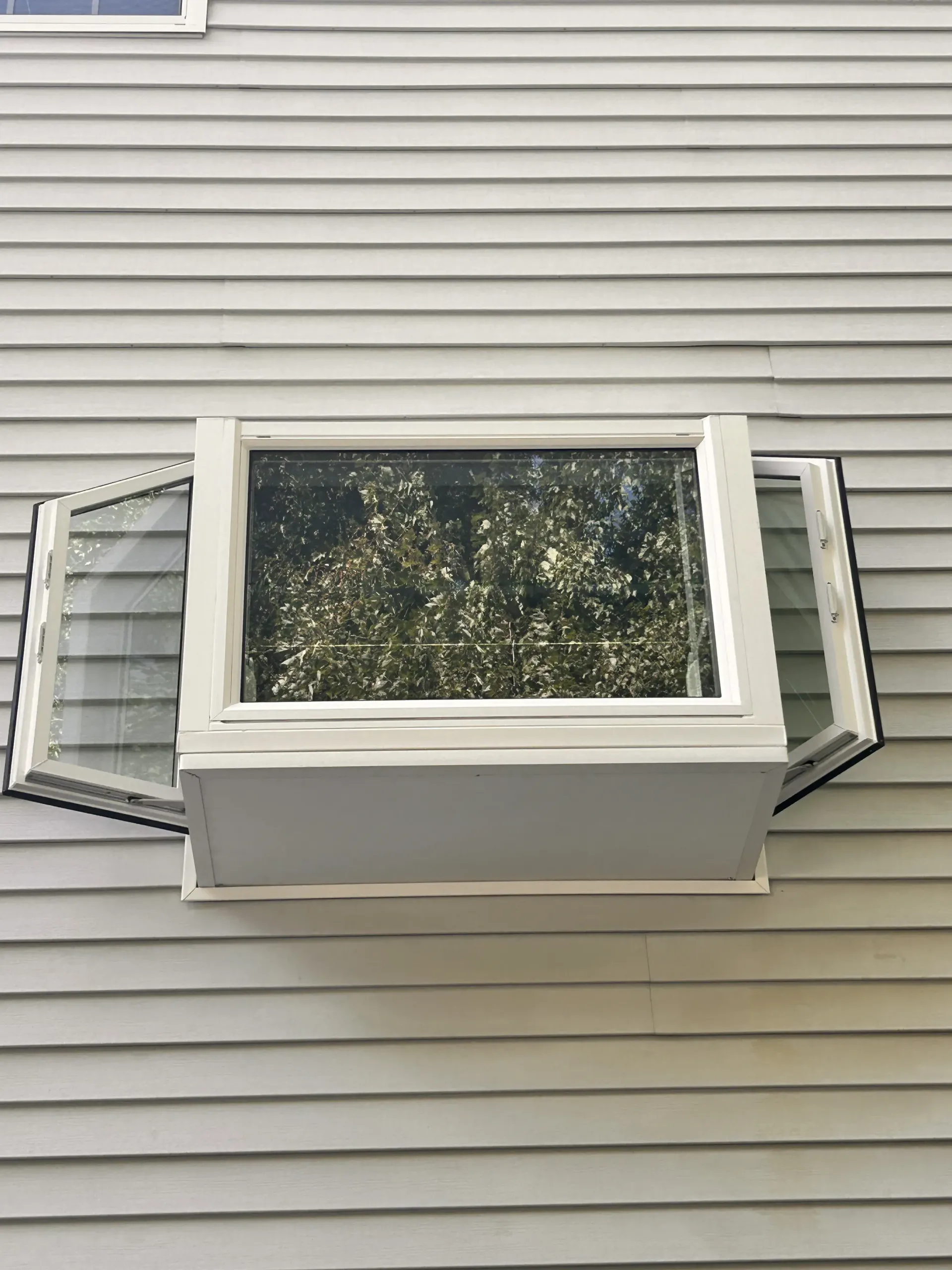 White house exterior with an open window air conditioner and green shutters