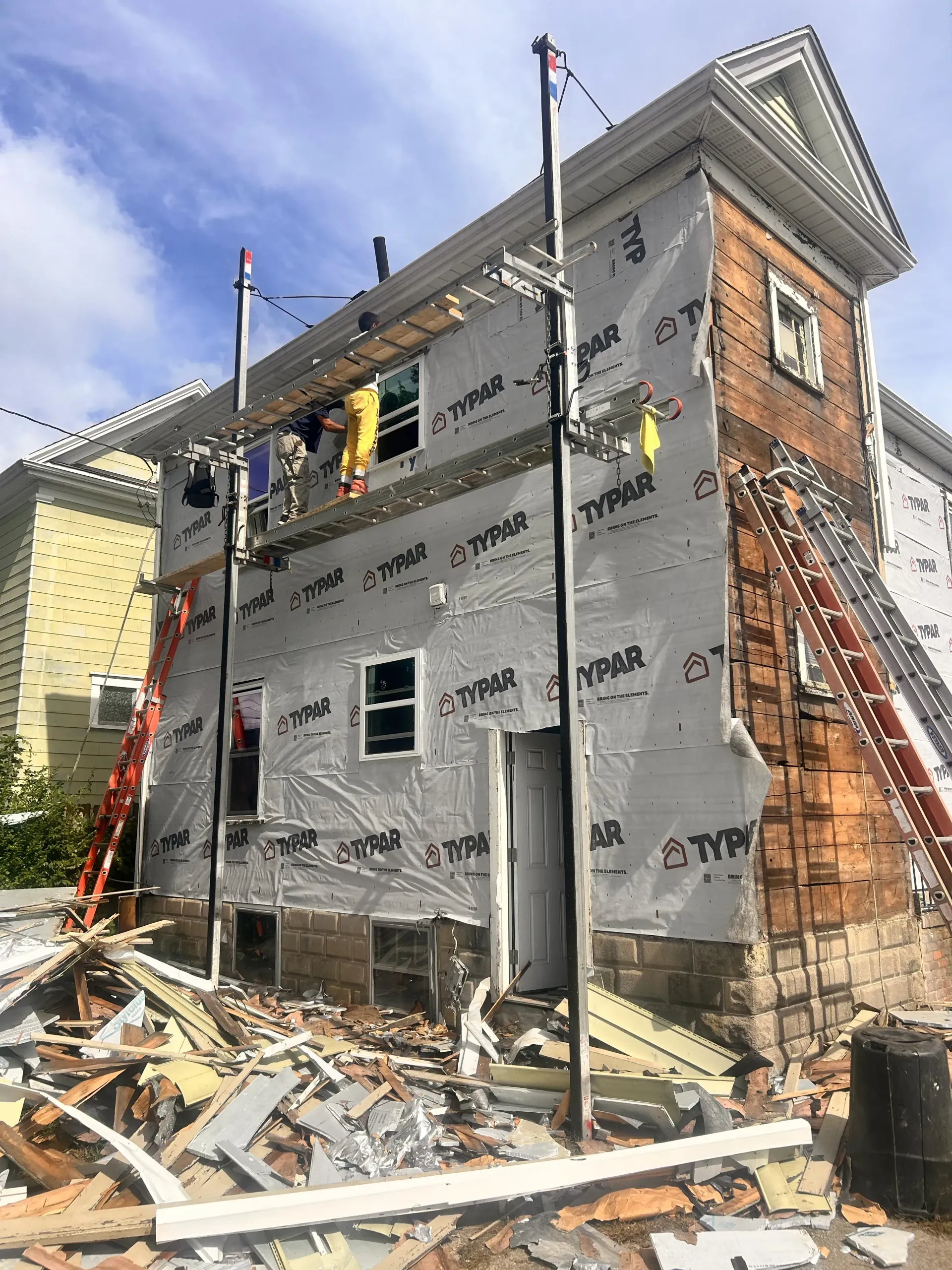 Partially demolished brick house under renovation with exposed framing and construction debris