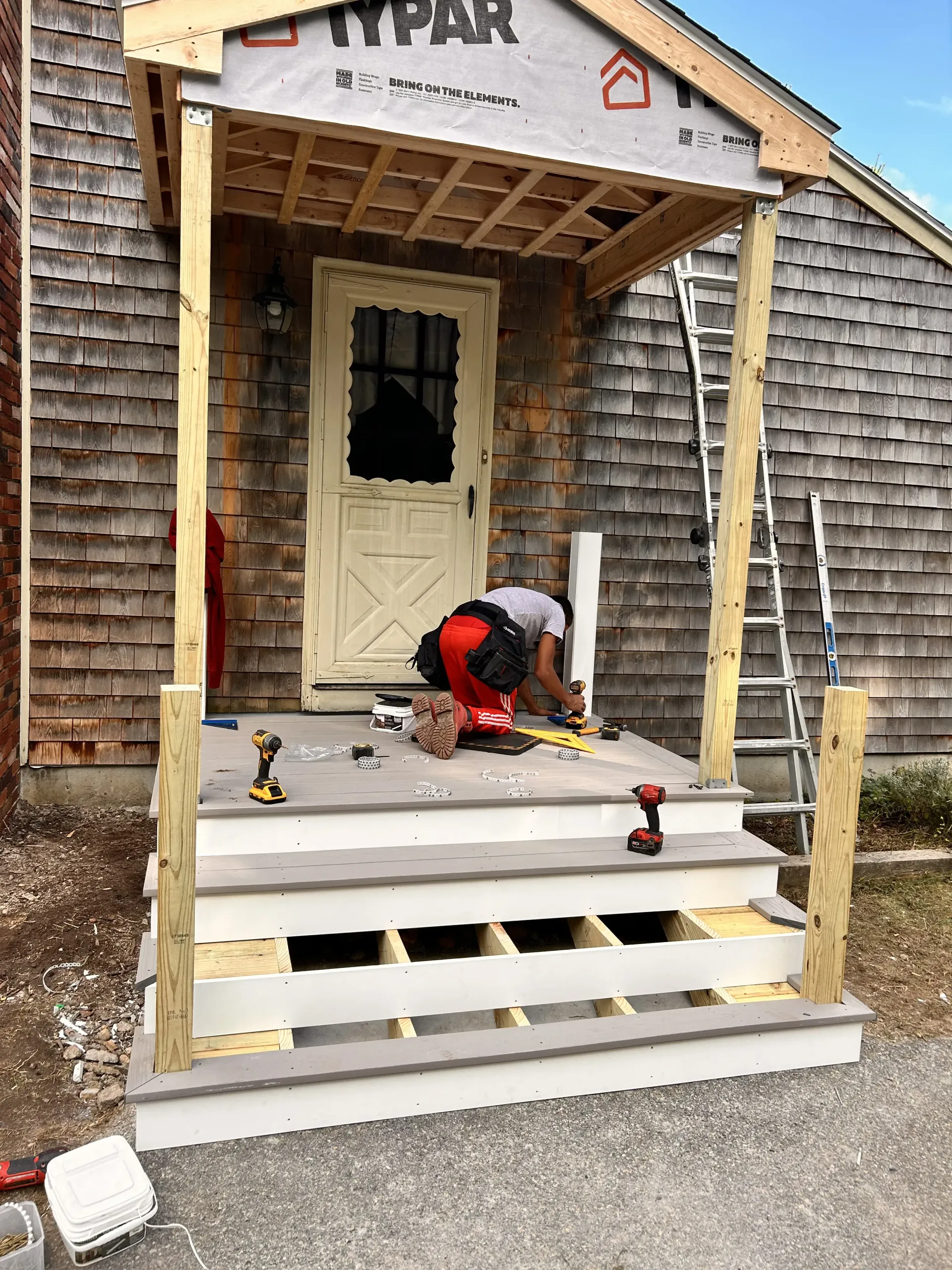 Worker installing porch steps on a house under construction