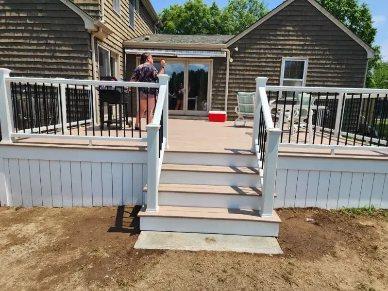 White deck stairs leading to a house patio, with two people standing near the entrance.
