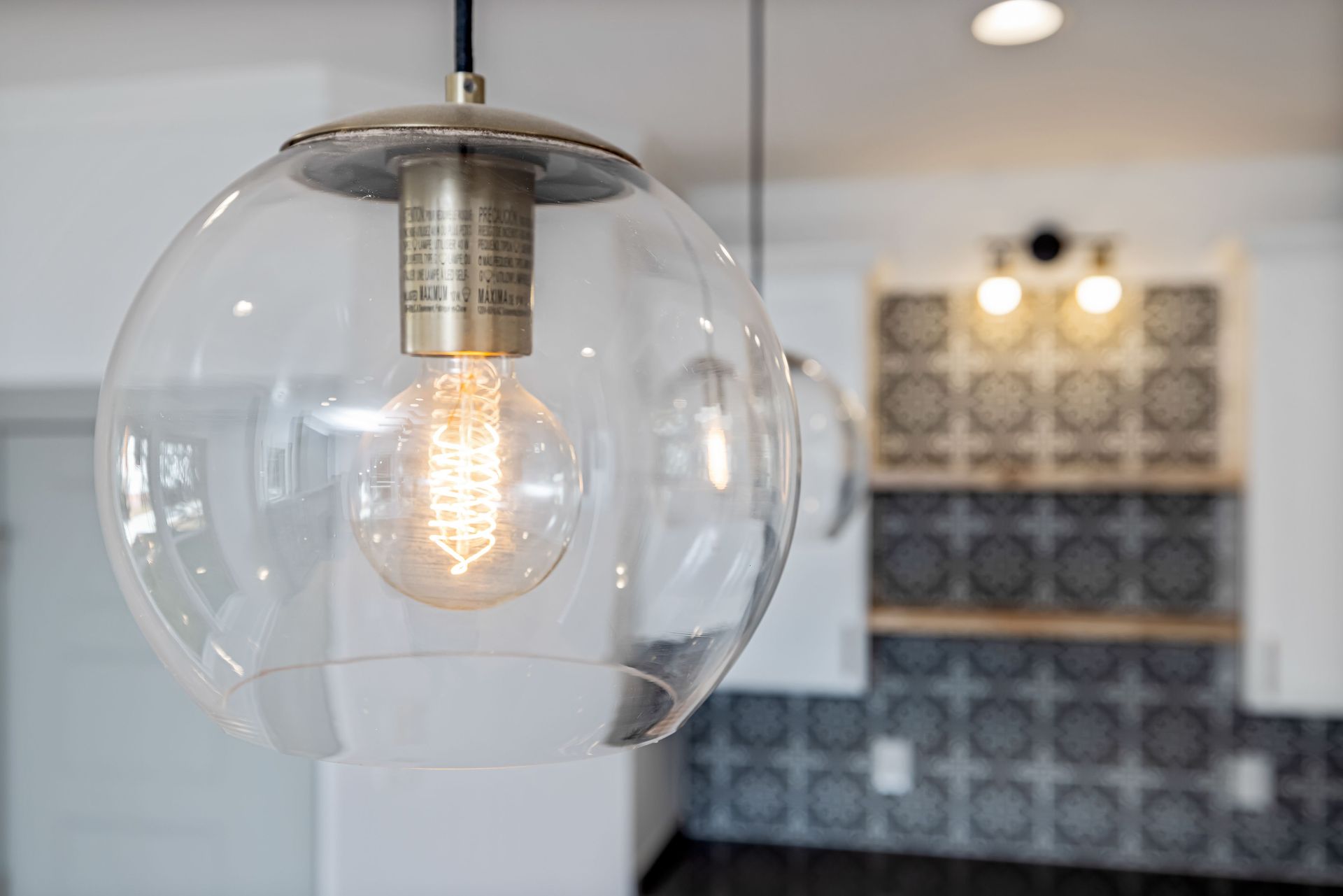 Clear glass pendant light with exposed bulb hanging in a modern kitchen