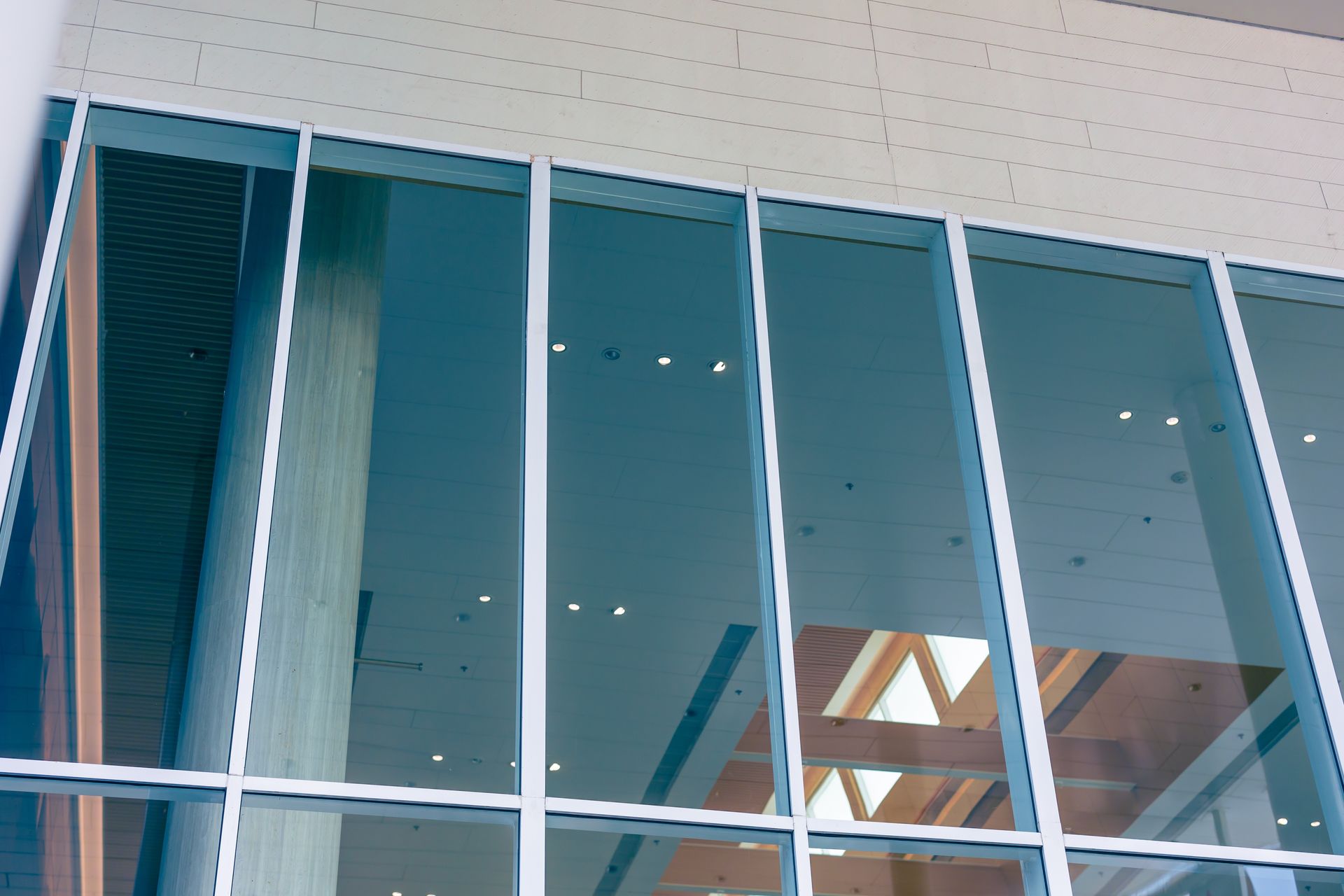 Modern glass building facade with reflective windows and visible wooden beams inside