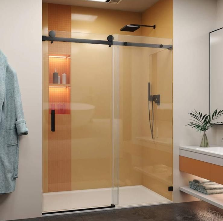 Modern walk-in shower with beige tile, glass door, black hardware, and built-in shelves with warm lighting.