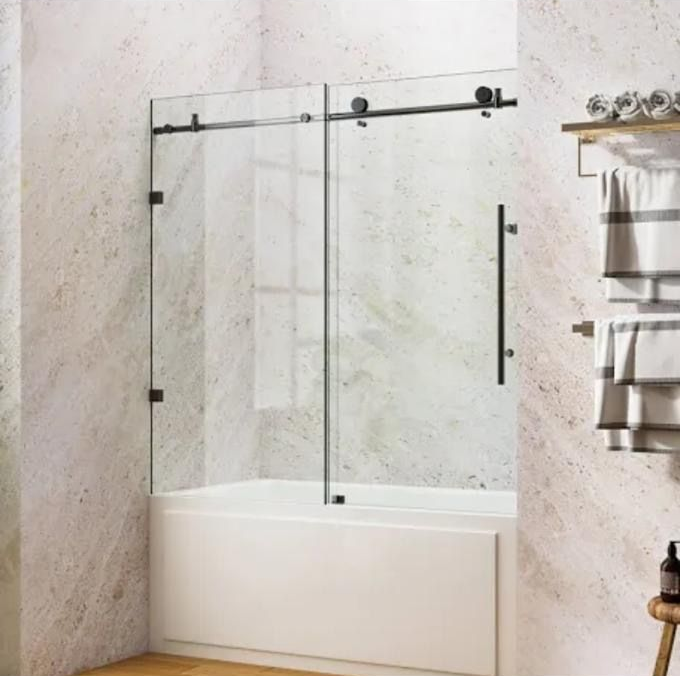 Frameless sliding glass shower door with black hardware in a modern beige bathroom