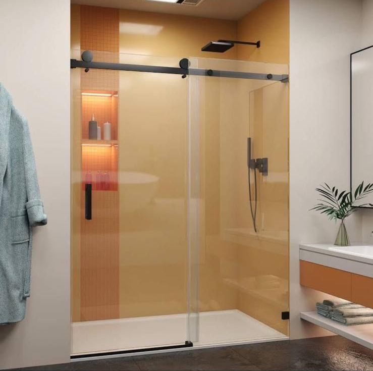 Modern bathroom shower with glass door, black hardware, and warm beige tile walls
