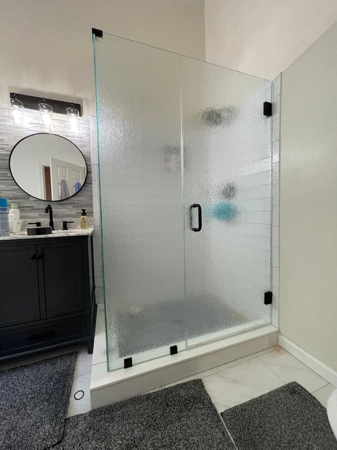 Glass shower enclosure with frosted panels in a bathroom beside a vanity and sink