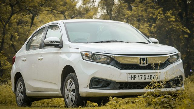White Honda sedan parked on grass in a wooded area