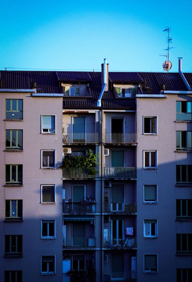 Apartment building facade with balconies and windows against a bright blue sky