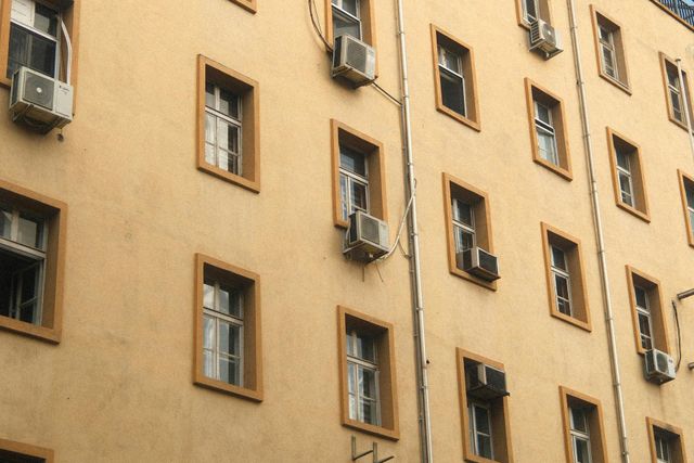 Tan apartment building facade with many windows and several air conditioners