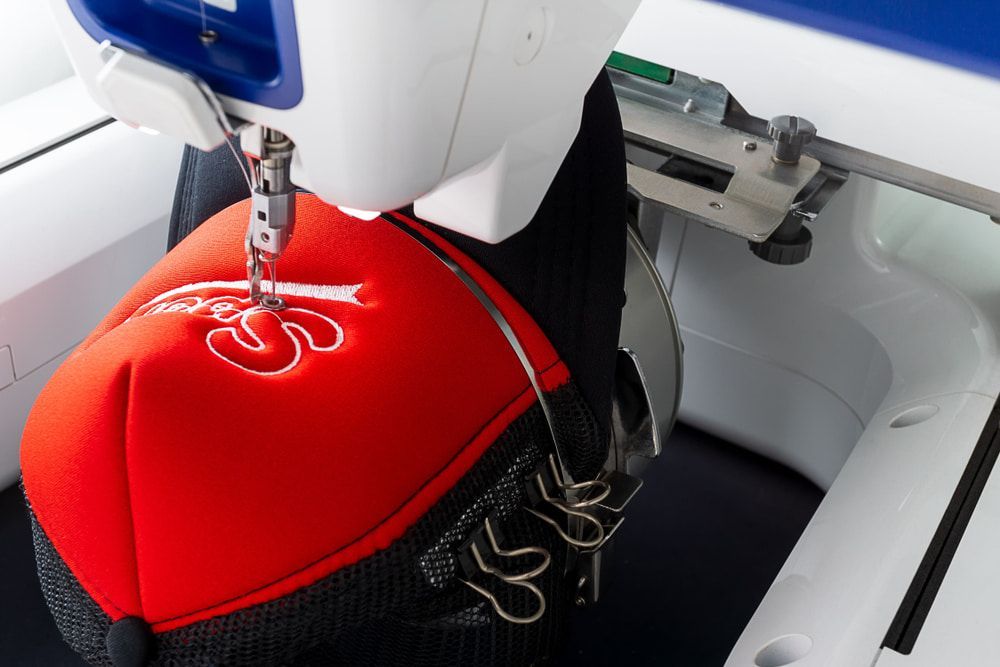 A Red Hat Is Being Embroidered on A Sewing Machine — CKM Screen Printing in Erina, NSW