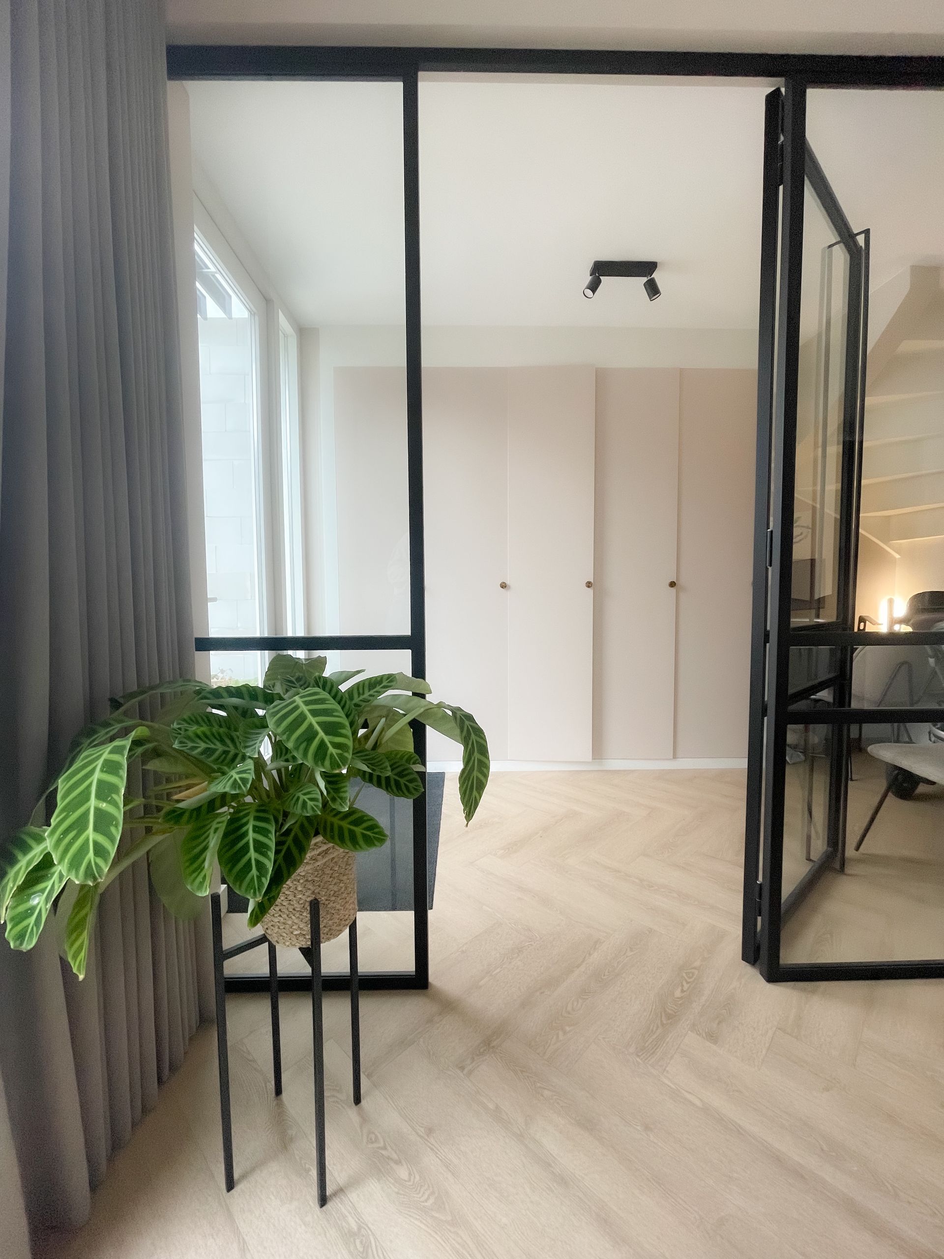 Glazen deuren met zwarte stalen frame die doorgang biedt naar de bijkeuken/werkkamer
