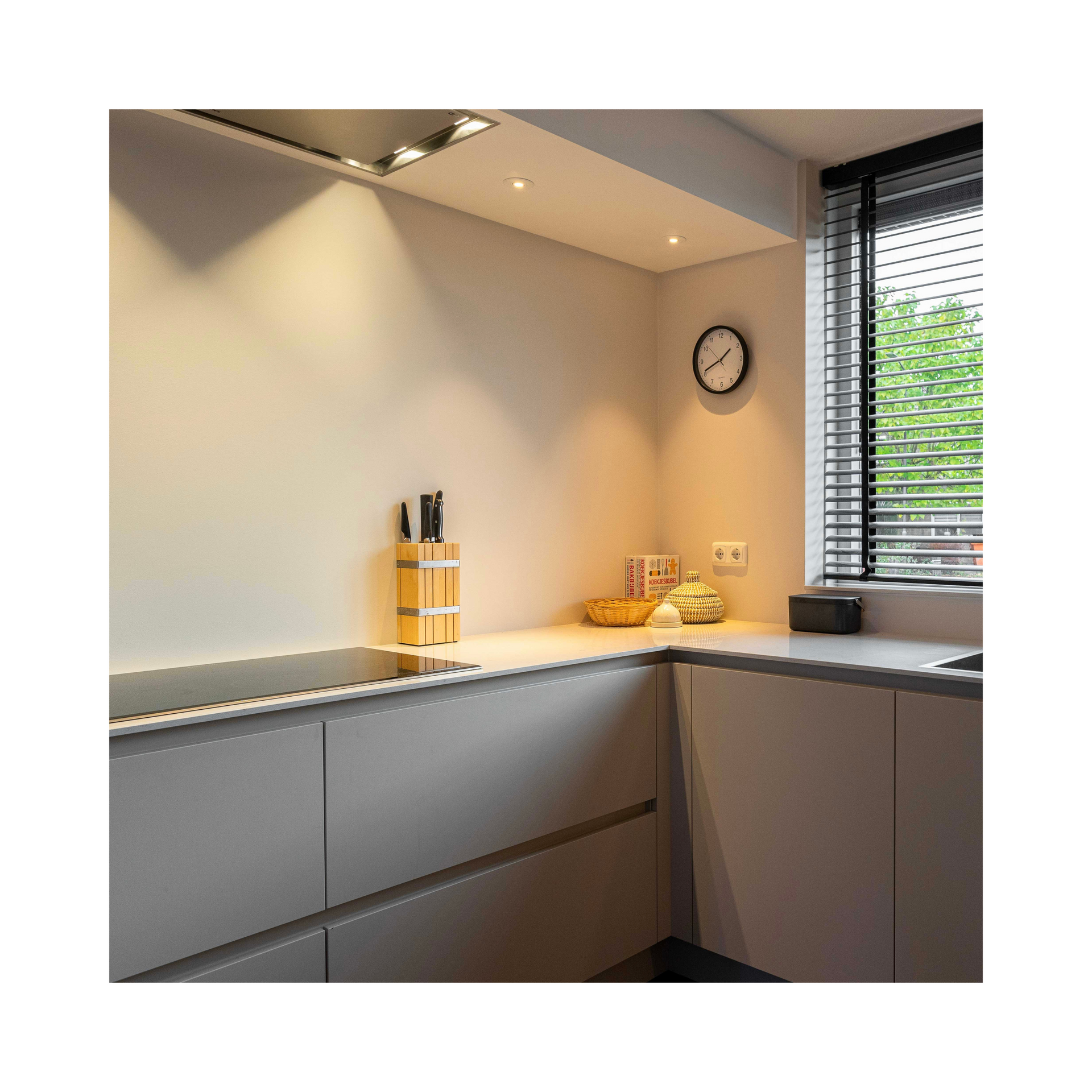 Een keuken met beige kasten en een klok aan de muur