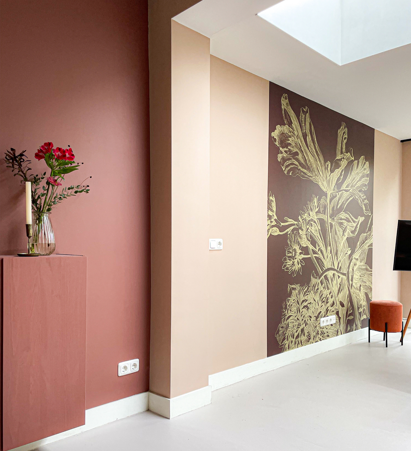 Een vaas met bloemen staat op een tafel voor een muur met een afbeelding van bloemen erop