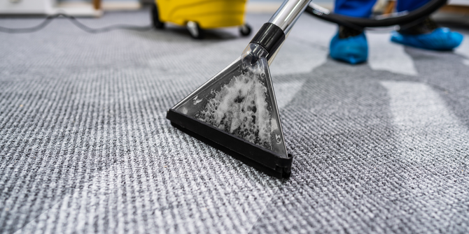 Carpet being cleaned with a machine, showing the cleaning head close up.