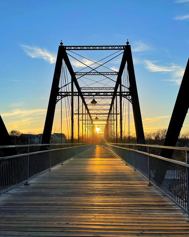 A bridge with the sun shining through it at sunset