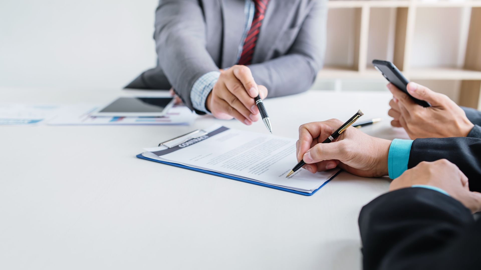 A group of business people are sitting at a table signing a document.