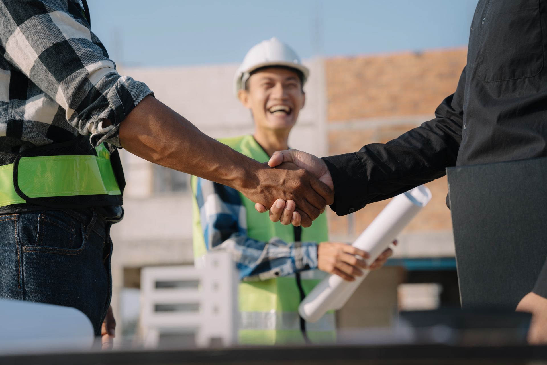 A group of construction workers are shaking hands on a construction site.