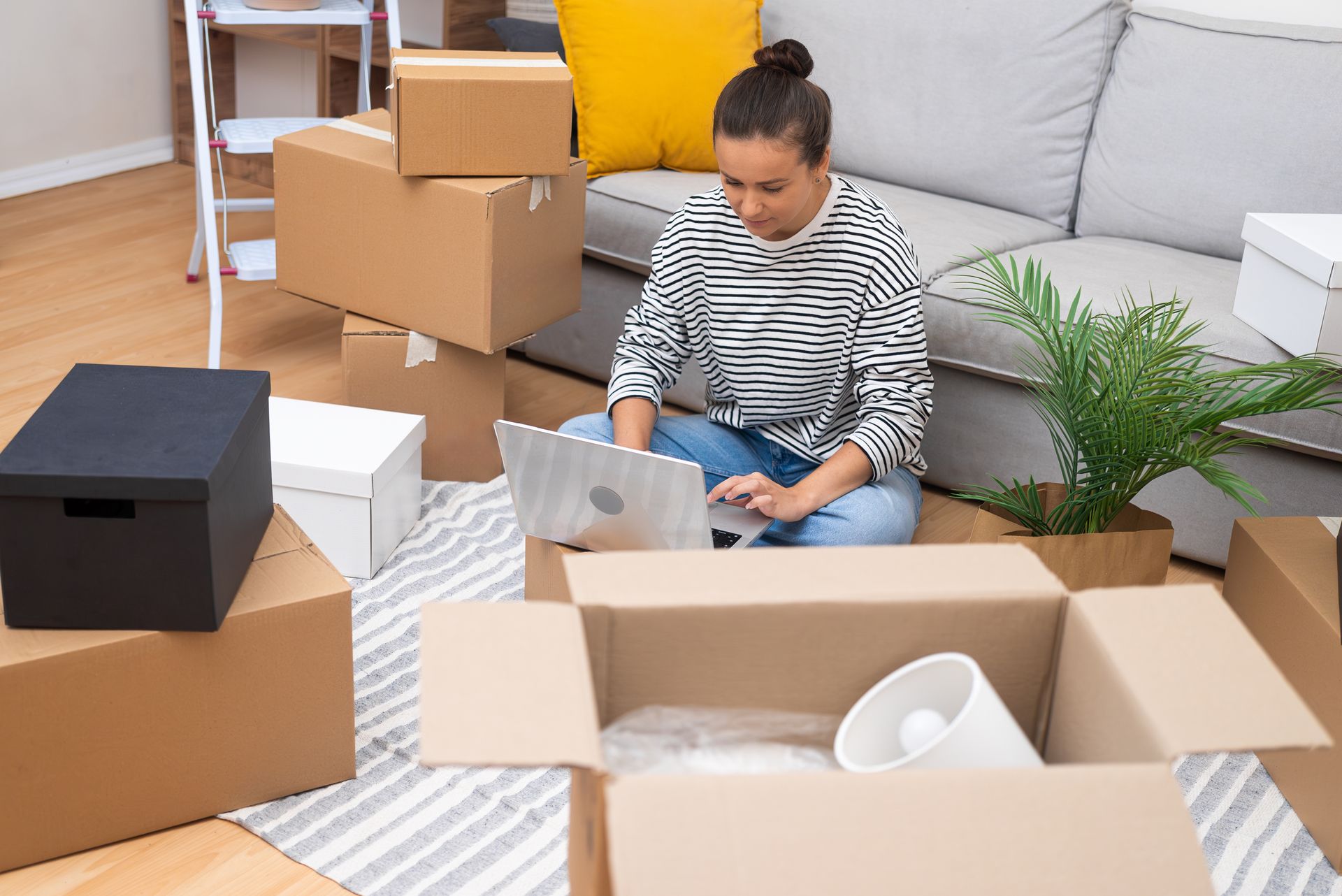 A woman is sitting on the floor in a living room using a laptop computer.