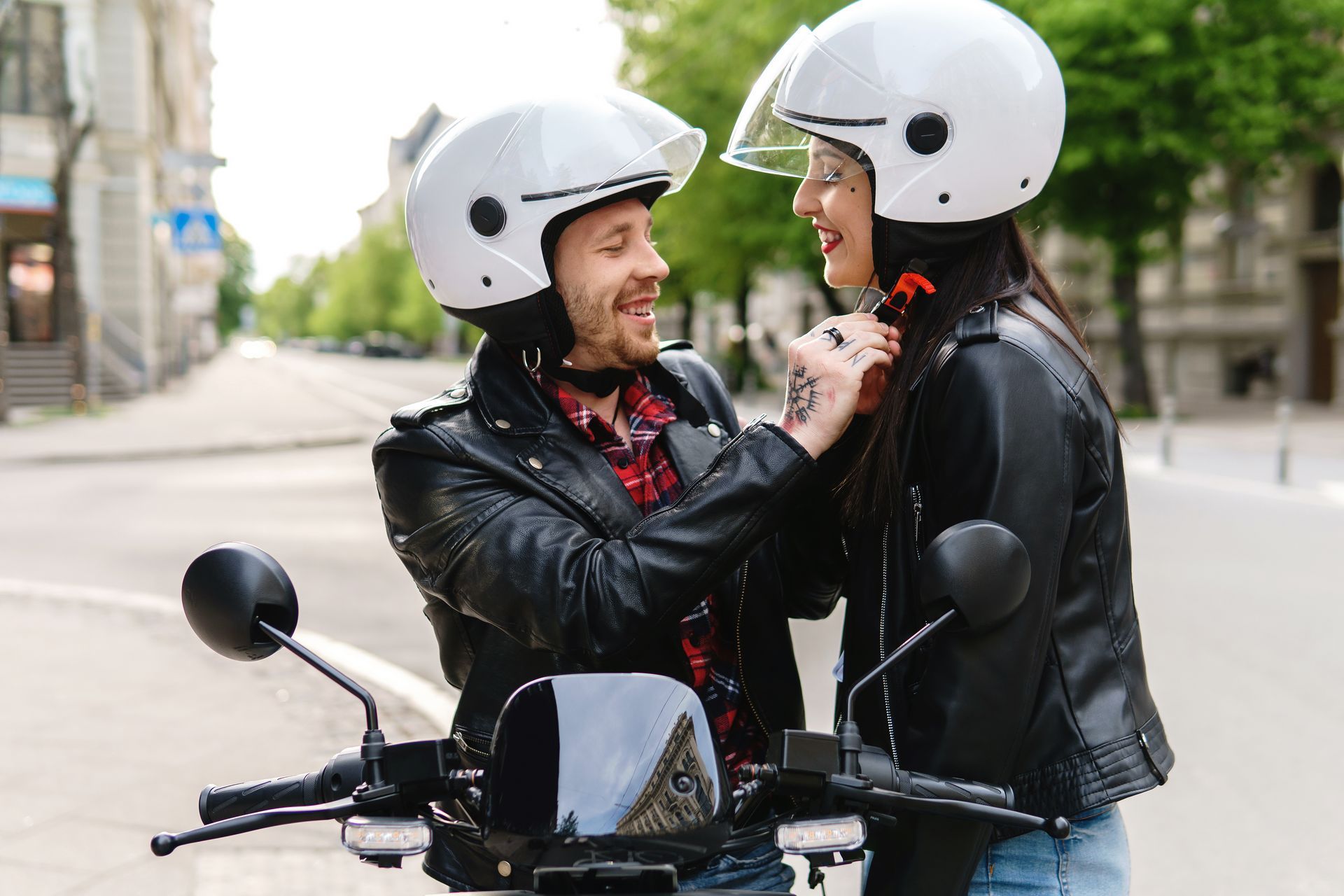 A man and a woman wearing helmets are standing next to each other on a motorcycle.