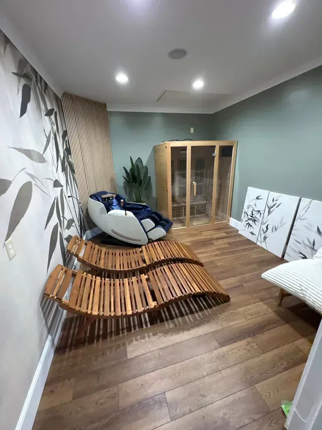Modern living room with curved wooden lounge chair, sofa, wood floor, and glass cabinet under recessed lights