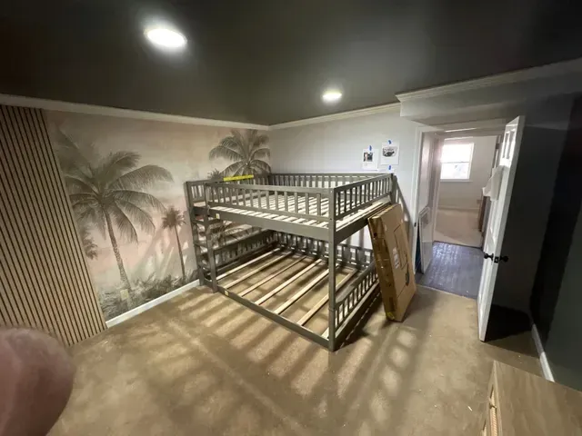 Bedroom with bunk bed, palm mural wall, and hallway doorway under warm ceiling lights