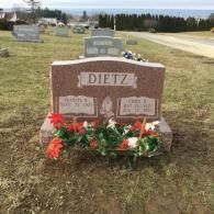 A gravestone in a cemetery with flowers on it.