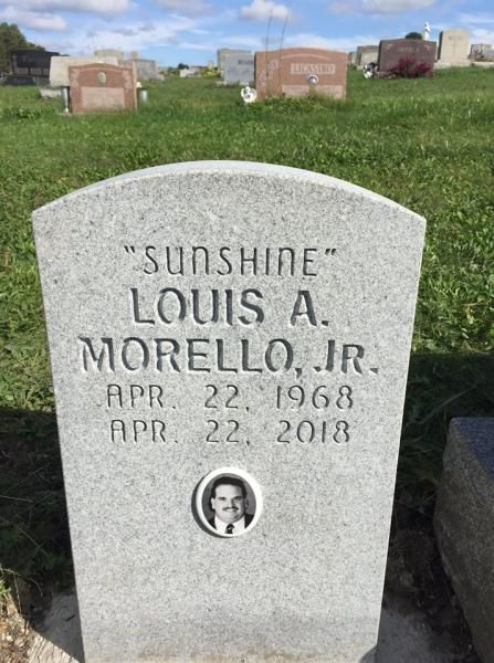 A gravestone for louis a. morello jr. in a cemetery.