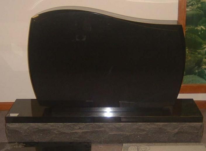 A black gravestone is sitting on top of a gray base.