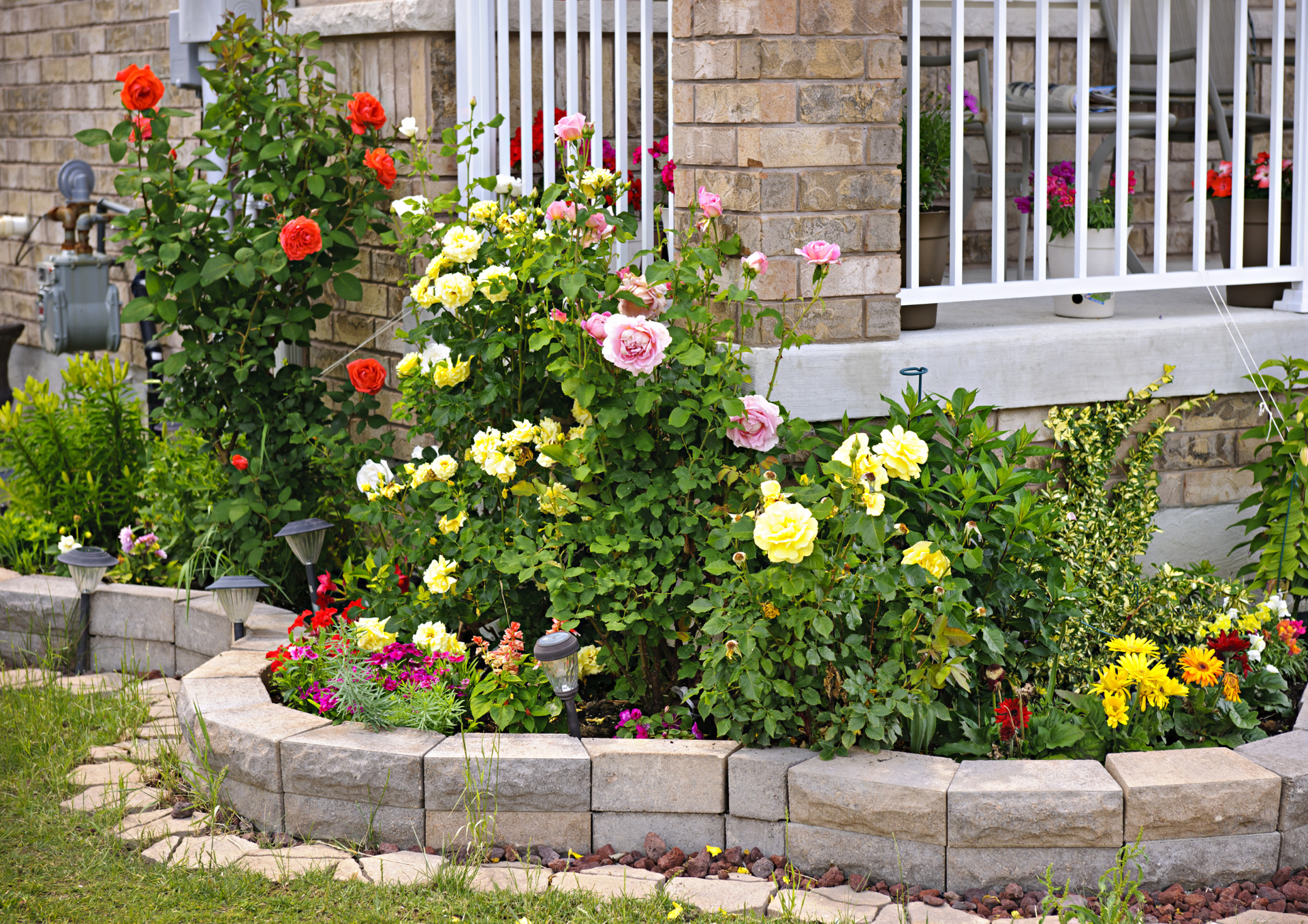 Brick house front entry with stone stepping path, landscaped grasses, and wrought-iron door