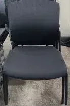 A black chair is sitting on a tiled floor next to a table.