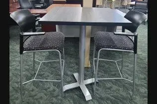 A table and chairs are sitting on a green carpet in a room.
