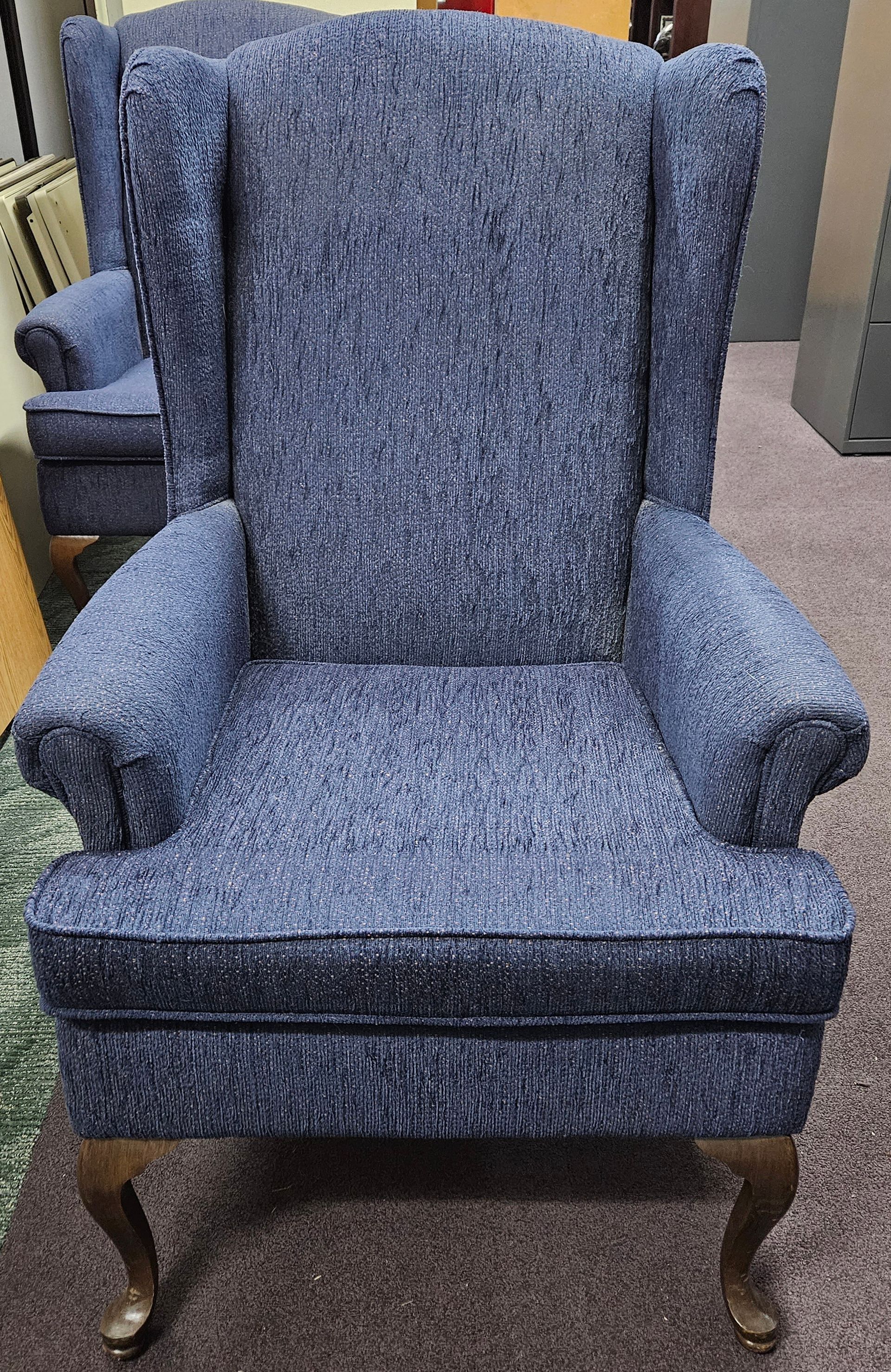 A blue chair is sitting on a carpet in a room.