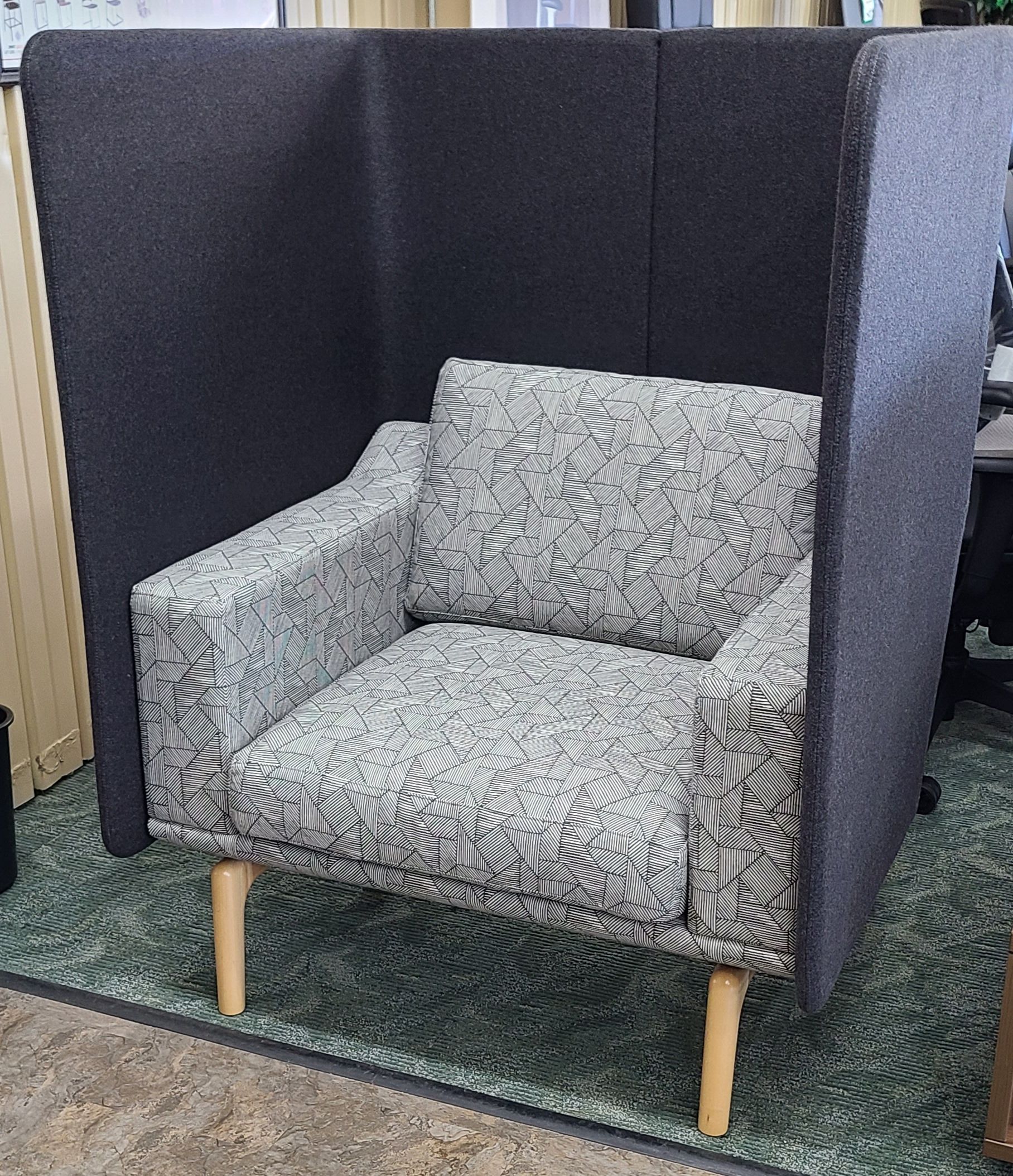 A chair is sitting in a cubicle in a room.