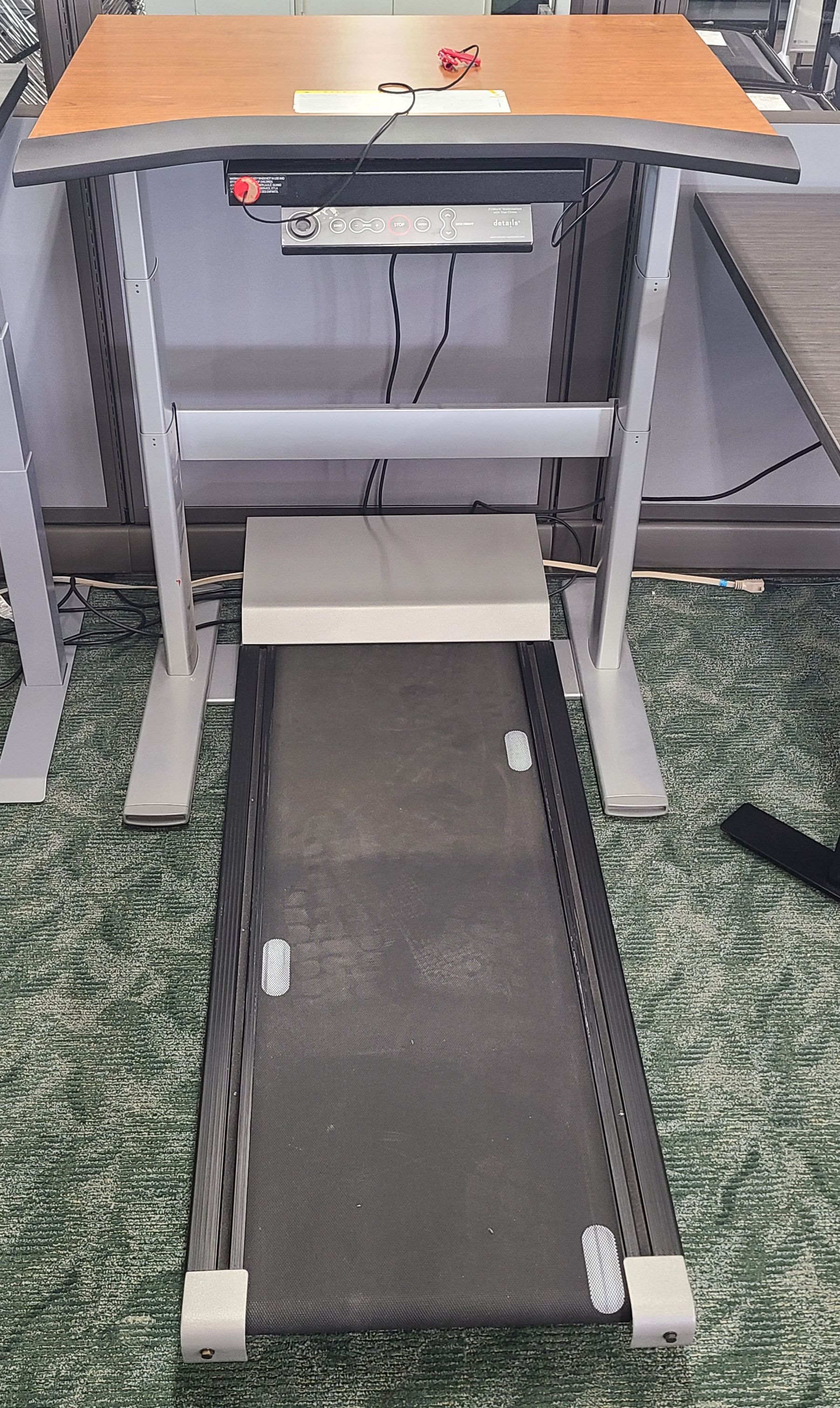 A treadmill is sitting under a desk in an office.