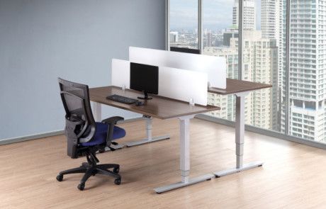 A standing desk with a computer on it and a chair in an office.